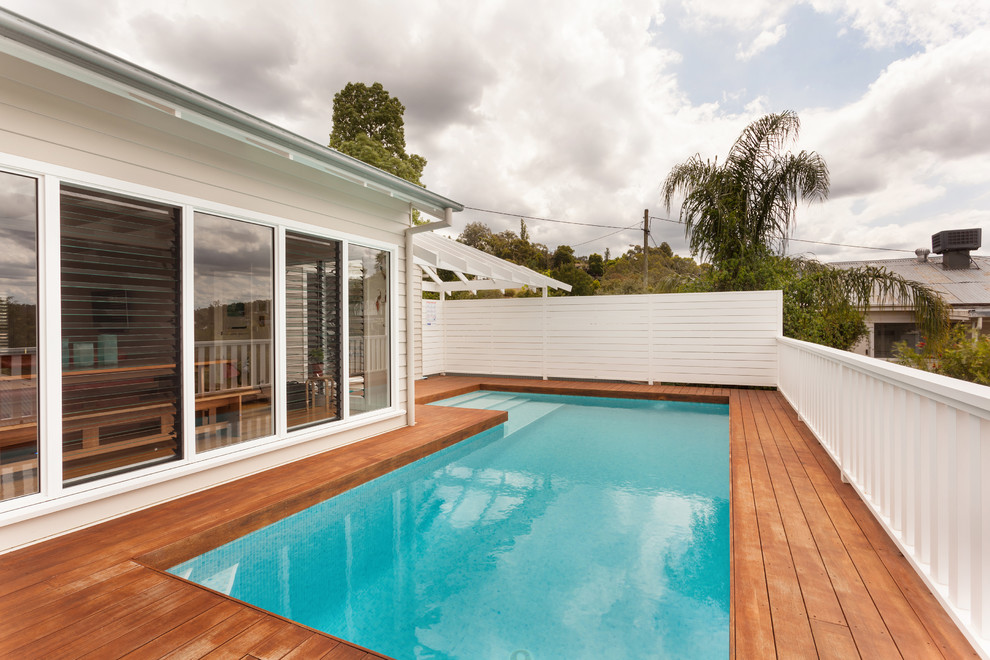 Cette image montre une piscine sur toit hors-sol marine en L de taille moyenne avec une terrasse en bois.