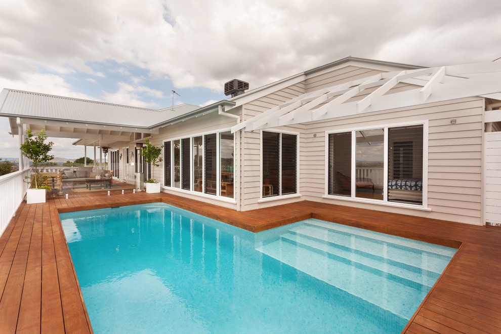 Idée de décoration pour une piscine sur toit hors-sol marine en L de taille moyenne avec une terrasse en bois.