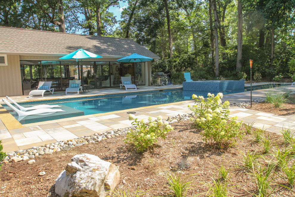 Photo of a large classic side rectangular lengths swimming pool in Other with a pool house and natural stone paving.