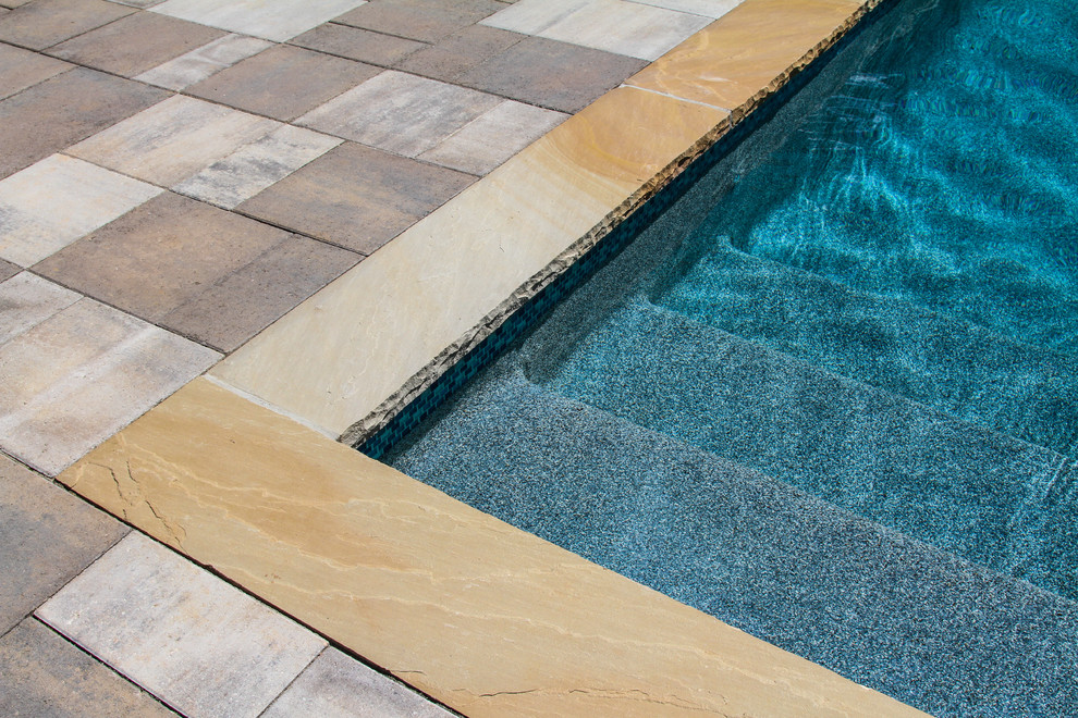 Inspiration pour une grande piscine latérale craftsman rectangle avec des pavés en pierre naturelle.