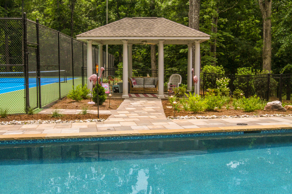 Ejemplo de casa de la piscina y piscina alargada de estilo americano grande rectangular en patio lateral con adoquines de piedra natural
