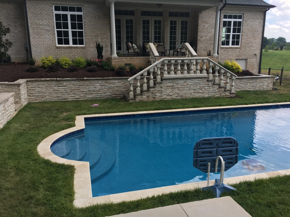 Foto de piscina alargada tradicional grande rectangular en patio trasero con adoquines de piedra natural