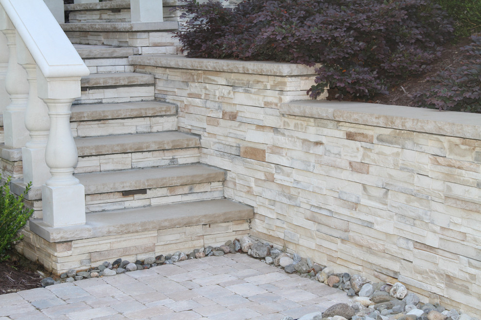 Modelo de piscina alargada clásica grande rectangular en patio trasero con adoquines de piedra natural