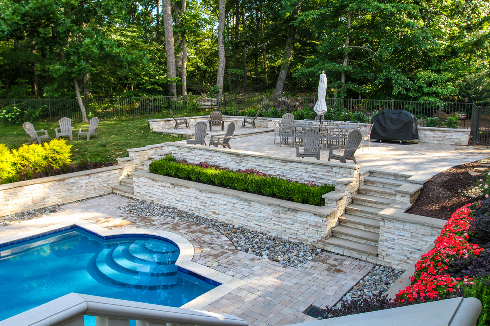 Imagen de piscina alargada clásica grande rectangular en patio trasero con adoquines de piedra natural