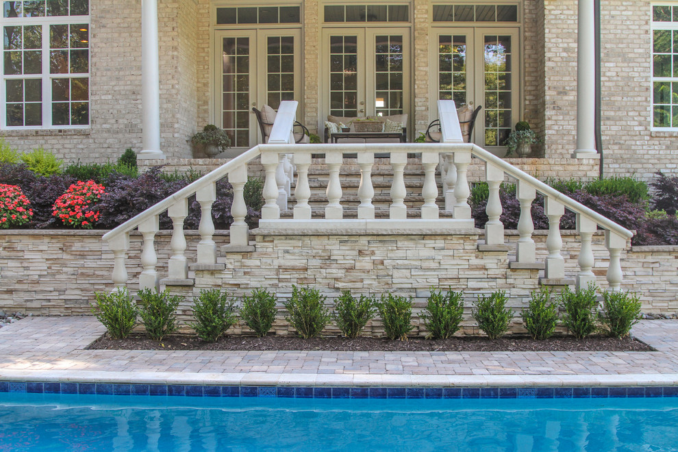 Ispirazione per una grande piscina monocorsia chic rettangolare dietro casa con pavimentazioni in pietra naturale