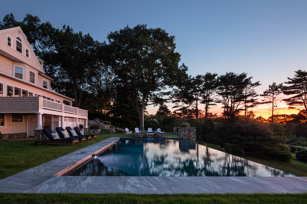 Inspiration for a large traditional back rectangular infinity swimming pool in Portland Maine with a pool house and concrete slabs.