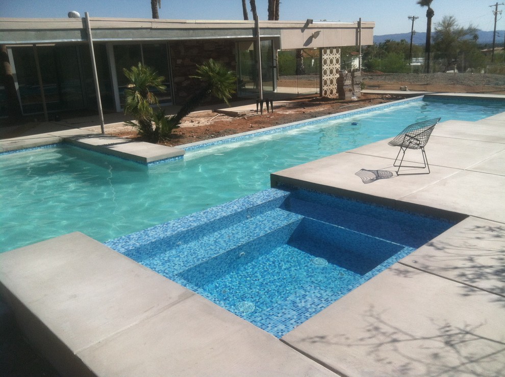 Idee per una grande piscina monocorsia minimalista rettangolare dietro casa con una vasca idromassaggio e cemento stampato