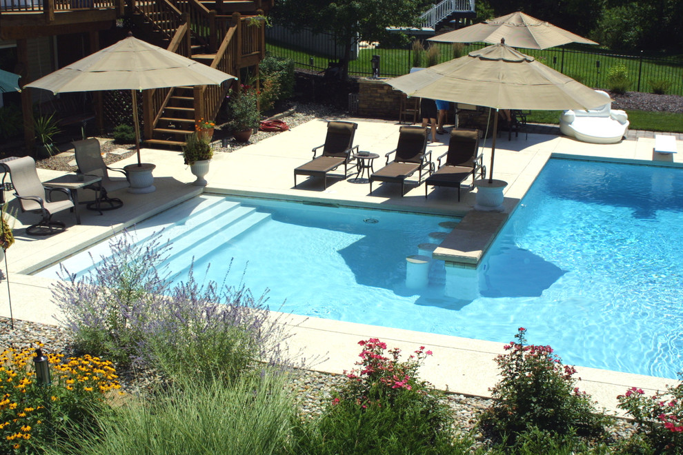 Idée de décoration pour une grande piscine arrière tradition en L avec du béton estampé.