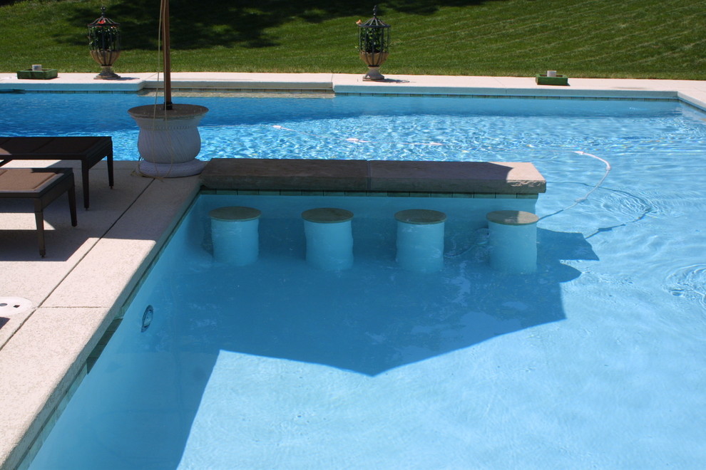 Пример оригинального дизайна: большой спортивный, угловой бассейн на заднем дворе в классическом стиле с покрытием из декоративного бетона