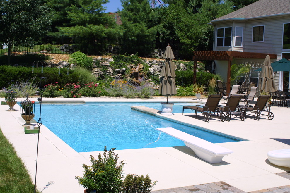 Immagine di una grande piscina classica a "L" dietro casa con cemento stampato