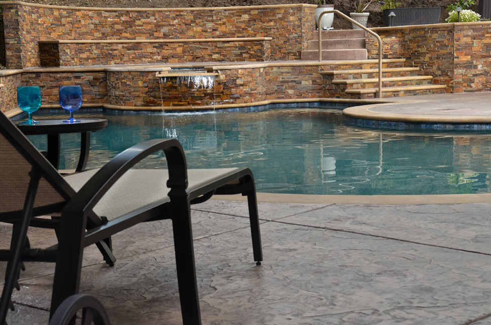 Diseño de piscinas y jacuzzis clásicos renovados grandes a medida en patio trasero con suelo de hormigón estampado