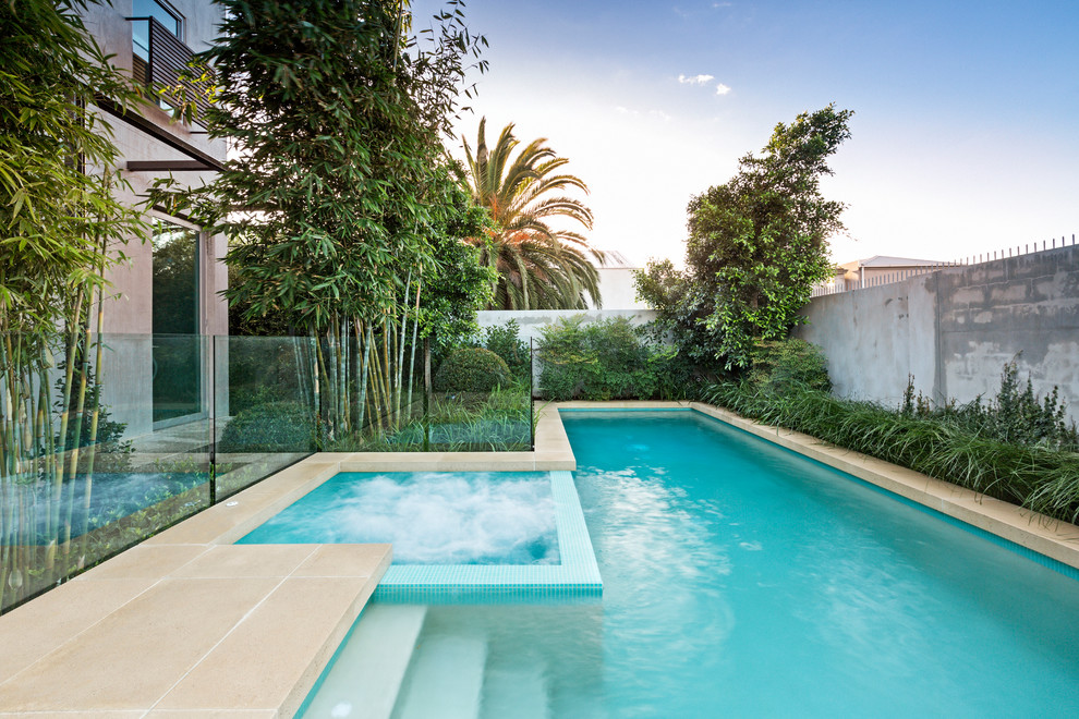 Idee per una piscina a sfioro infinito design rettangolare dietro casa e di medie dimensioni con pavimentazioni in cemento e una vasca idromassaggio