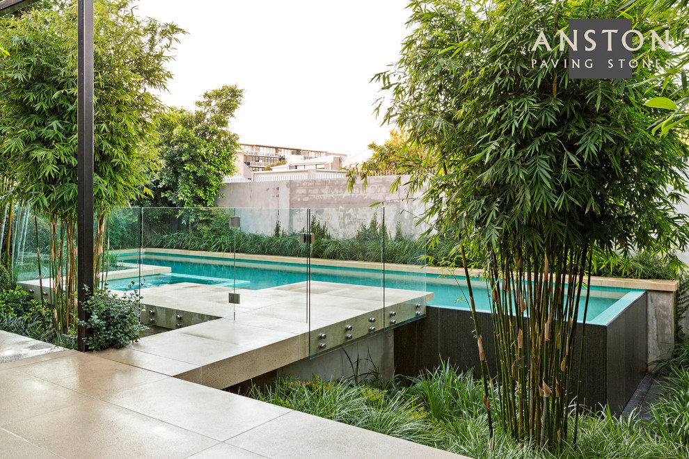Imagen de piscina moderna a medida en patio trasero con adoquines de hormigón