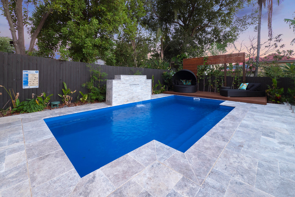 Foto på en mellanstor tropisk pool på baksidan av huset, med naturstensplattor
