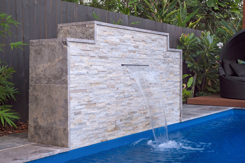 Ejemplo de piscina exótica de tamaño medio en patio trasero con adoquines de piedra natural