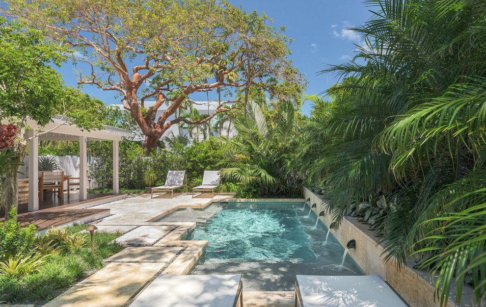 Imagen de piscina con fuente alargada tropical pequeña a medida en patio trasero con suelo de baldosas