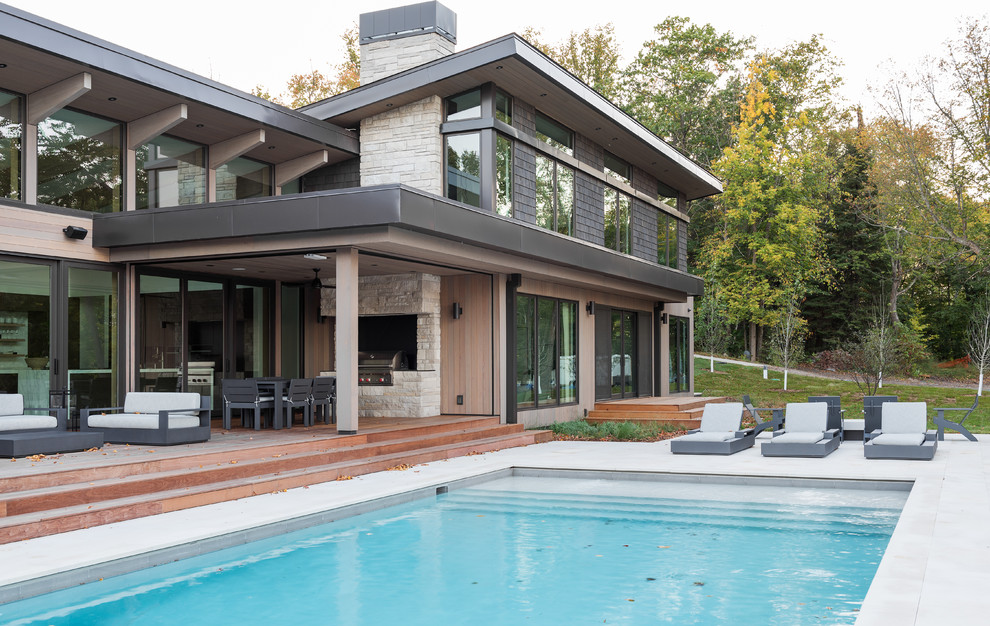 Imagen de piscina natural retro grande rectangular en patio trasero con adoquines de piedra natural