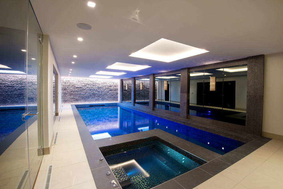Contemporary indoor rectangular swimming pool in Cheshire with a pool house and tiled flooring.