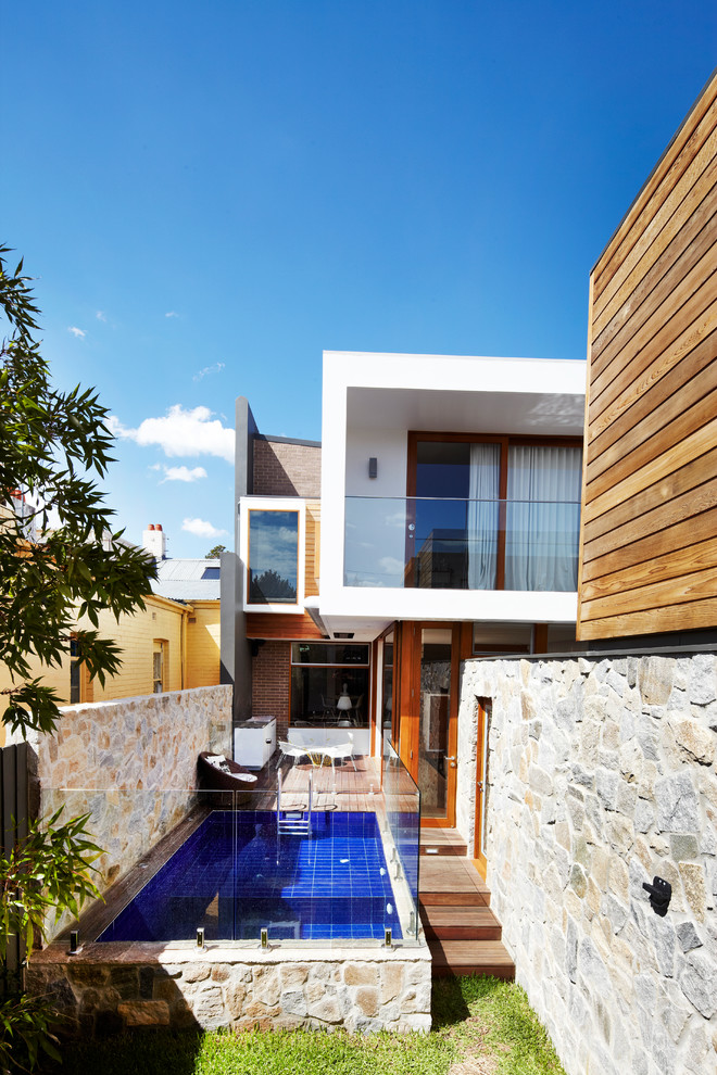 Ejemplo de piscina elevada actual de tamaño medio rectangular en patio lateral con entablado