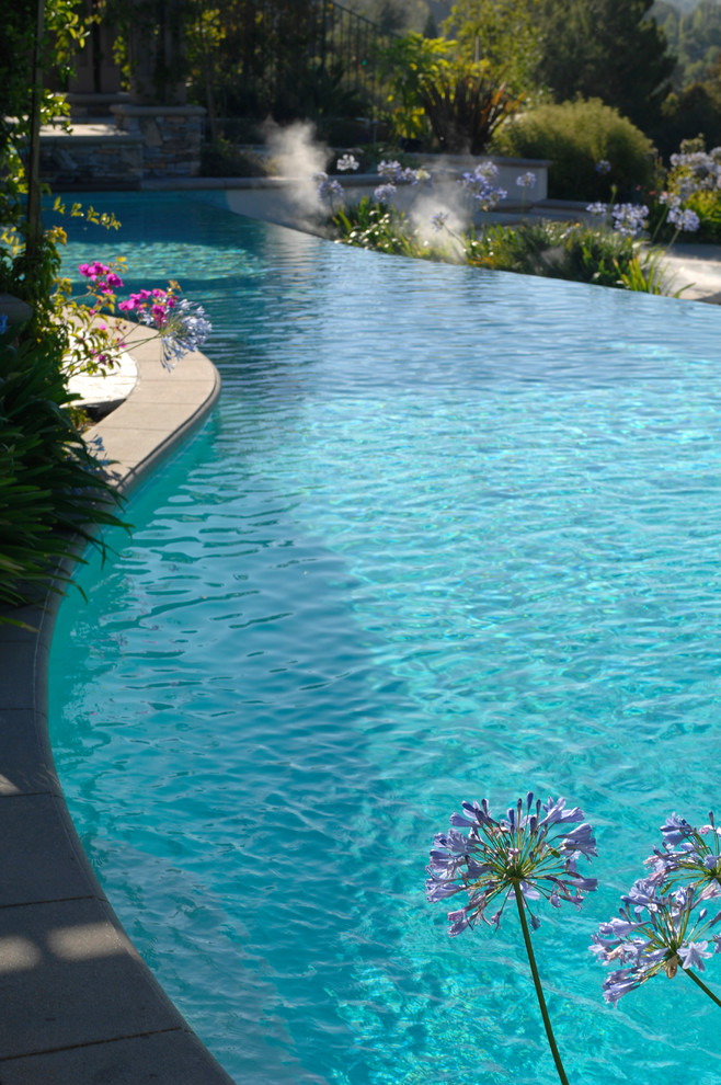 Свежая идея для дизайна: большой бассейн-инфинити произвольной формы на заднем дворе в современном стиле с водной горкой и покрытием из каменной брусчатки - отличное фото интерьера