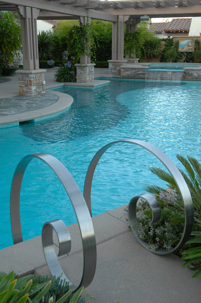 Modelo de piscina con tobogán infinita contemporánea grande a medida en patio trasero con adoquines de piedra natural