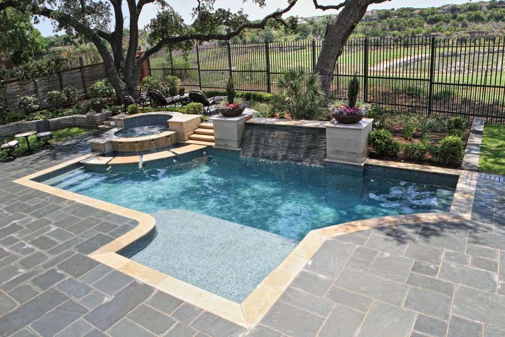 Esempio di una piscina classica personalizzata di medie dimensioni e dietro casa con una vasca idromassaggio e pavimentazioni in pietra naturale