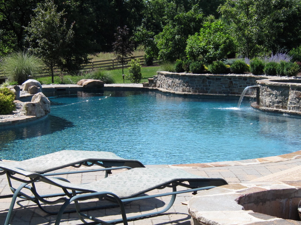Immagine di una grande piscina monocorsia rustica personalizzata dietro casa con fontane e piastrelle