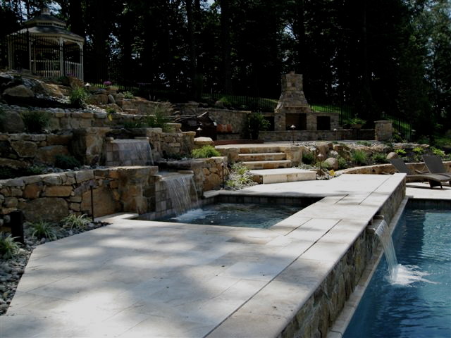 Ejemplo de piscina con fuente alargada tradicional grande rectangular en patio trasero con suelo de baldosas