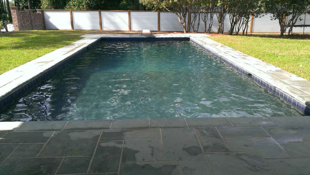 This is an example of a large back rectangular swimming pool in Jacksonville with natural stone paving.