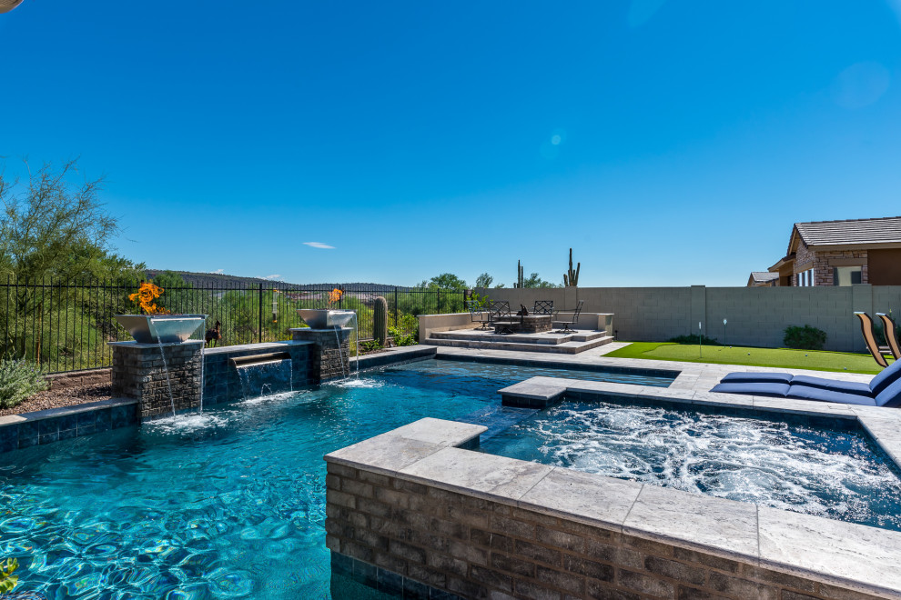 Esempio di una piscina stile americano rettangolare di medie dimensioni e dietro casa con una vasca idromassaggio e pavimentazioni in pietra naturale