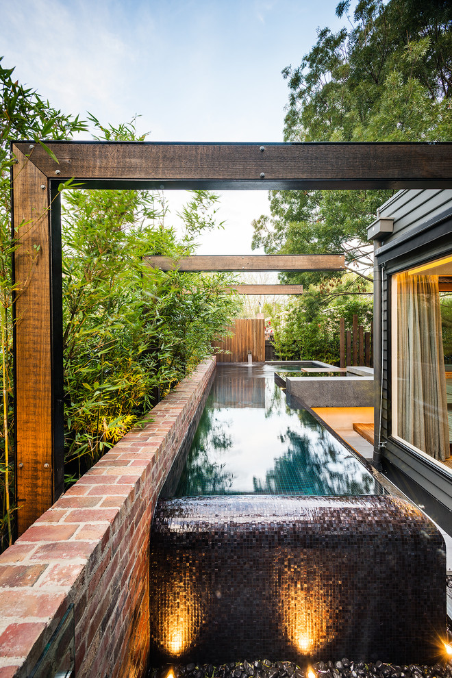 Immagine di una piscina a sfioro infinito design a "L" nel cortile laterale