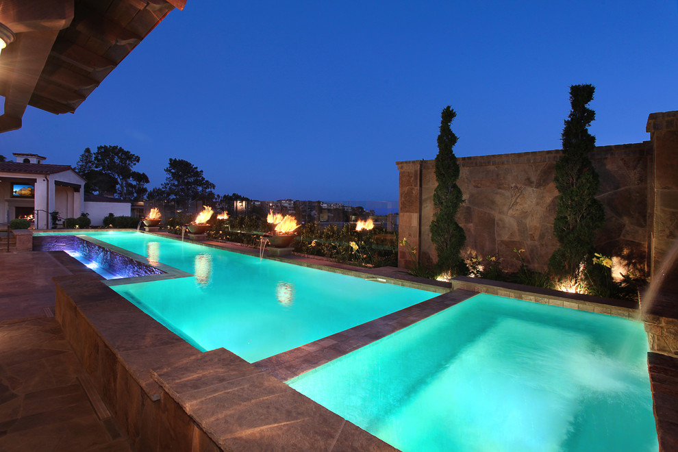 Photo of a large mediterranean back custom shaped lengths swimming pool in Orange County with a water feature and natural stone paving.