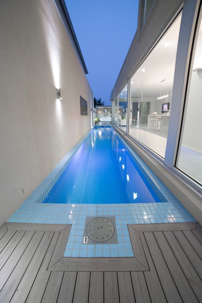 Diseño de piscina alargada moderna de tamaño medio rectangular en patio lateral con entablado