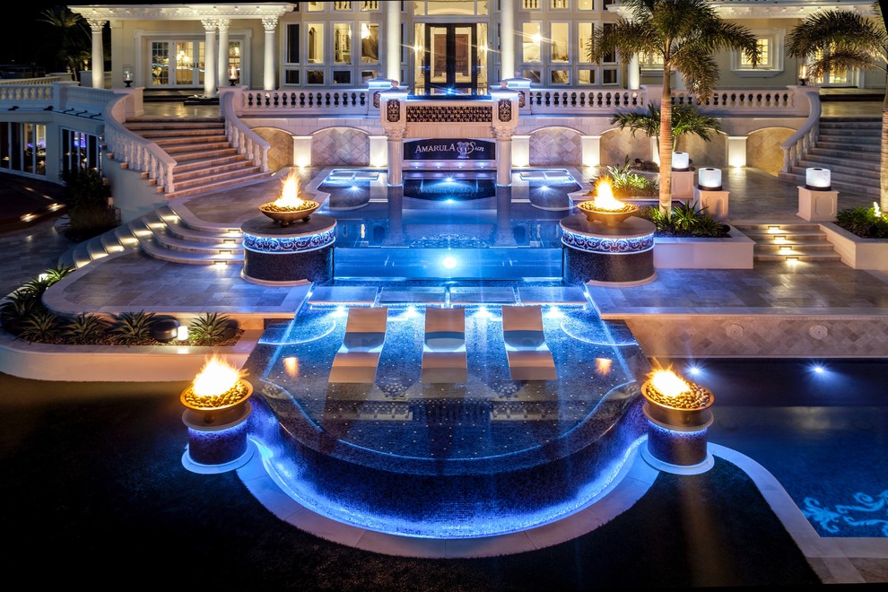 Example of a huge tuscan backyard stone and custom-shaped infinity hot tub design in Tampa