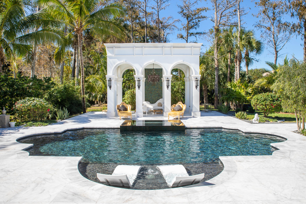 Example of a large tuscan backyard custom-shaped hot tub design in Miami