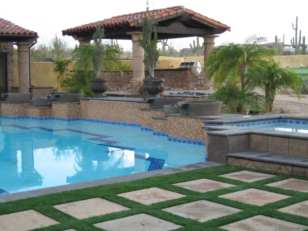 Medelhavsstil inredning av en stor anpassad pool på baksidan av huset, med poolhus och naturstensplattor