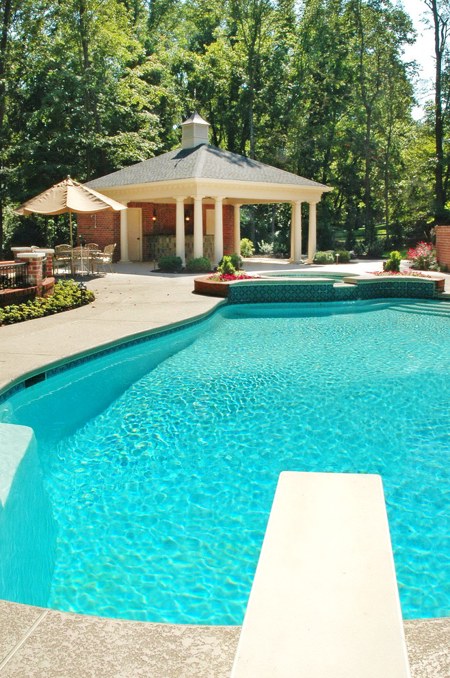 На фото: огромный бассейн произвольной формы на заднем дворе в классическом стиле с домиком у бассейна и мощением тротуарной плиткой