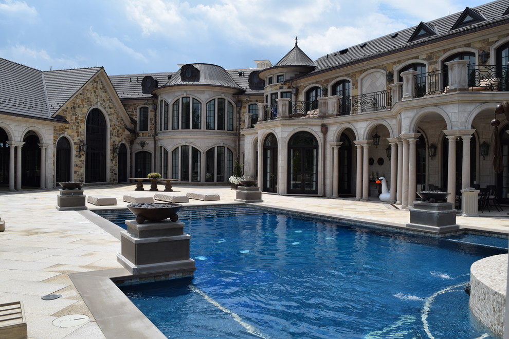 Стильный дизайн: огромный прямоугольный бассейн на заднем дворе в классическом стиле с джакузи и покрытием из каменной брусчатки - последний тренд