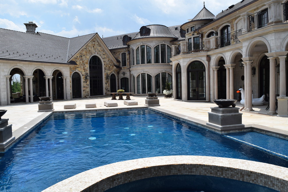 Modelo de piscinas y jacuzzis clásicos extra grandes rectangulares en patio trasero con adoquines de piedra natural