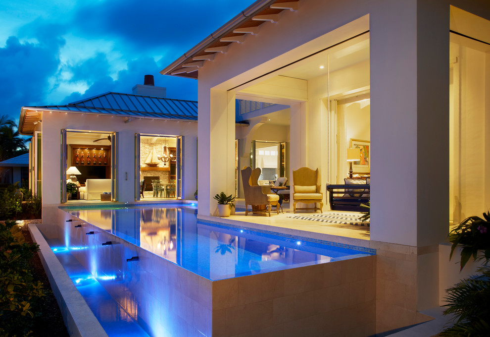 Ispirazione per un'ampia piscina a sfioro infinito tropicale personalizzata dietro casa con piastrelle e una vasca idromassaggio