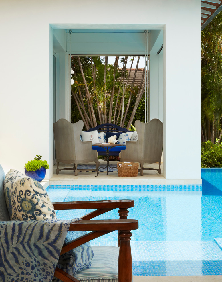 Immagine di un'ampia piscina a sfioro infinito tropicale personalizzata dietro casa con piastrelle e una vasca idromassaggio