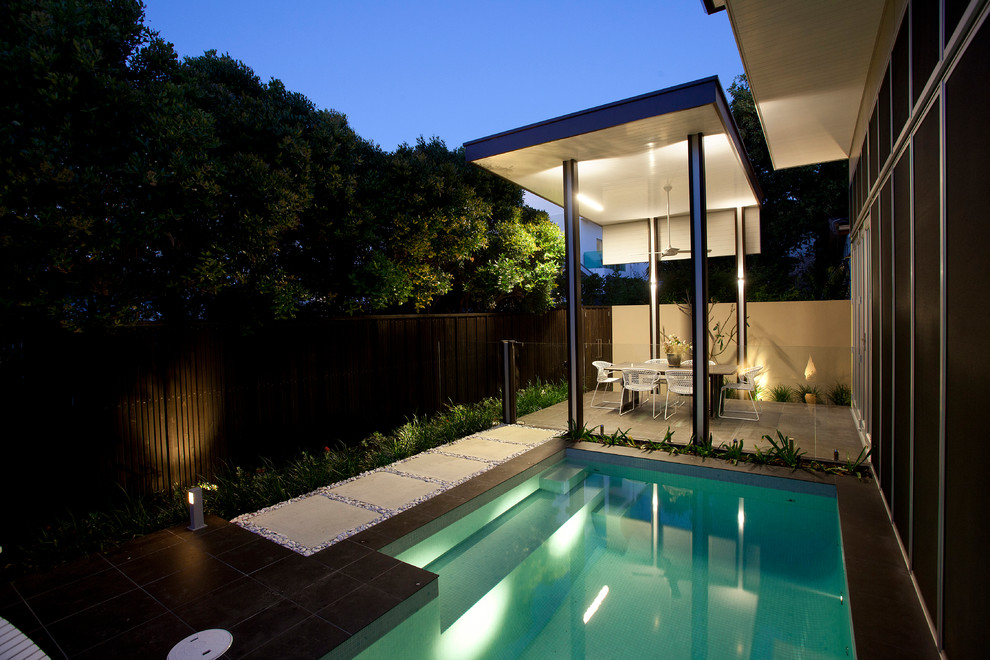 Foto de casa de la piscina y piscina alargada moderna de tamaño medio rectangular en patio lateral con adoquines de hormigón
