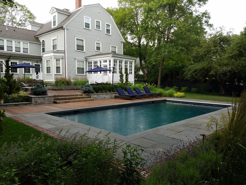 На фото: большой прямоугольный бассейн на заднем дворе в классическом стиле с покрытием из каменной брусчатки