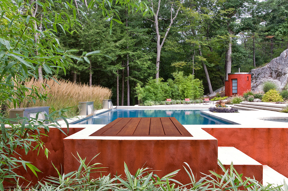Immagine di una grande piscina monocorsia contemporanea rettangolare dietro casa con una vasca idromassaggio e lastre di cemento