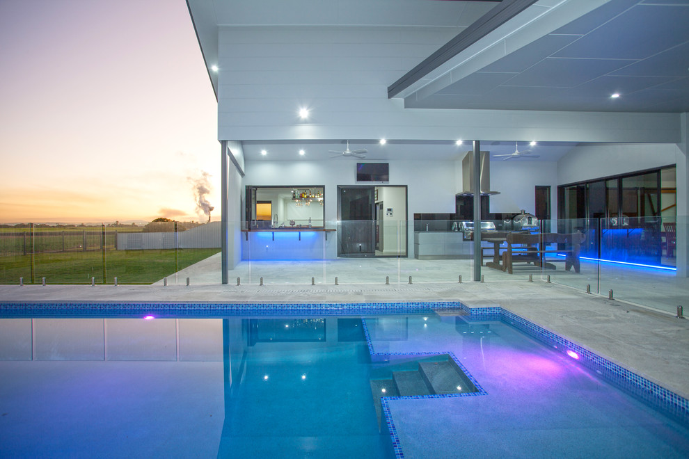 Modelo de piscina alargada minimalista de tamaño medio rectangular en patio trasero con suelo de baldosas