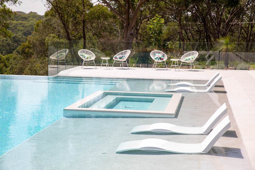 Immagine di una piscina a sfioro infinito design rettangolare dietro casa con una vasca idromassaggio