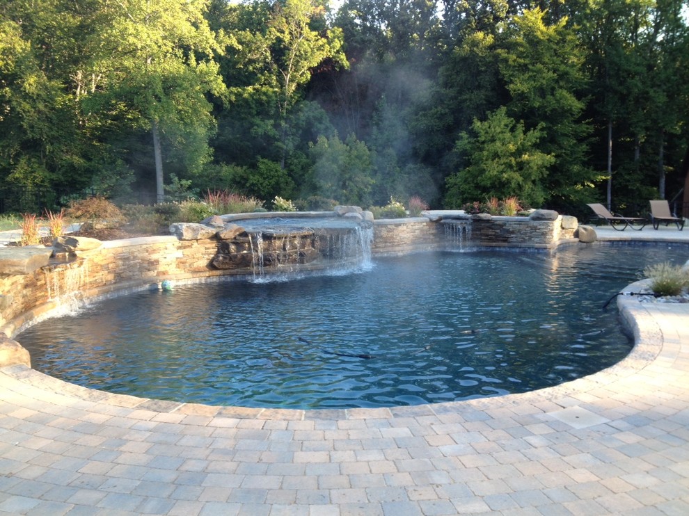 На фото: естественный бассейн среднего размера, произвольной формы на заднем дворе в стиле рустика с фонтаном и мощением тротуарной плиткой