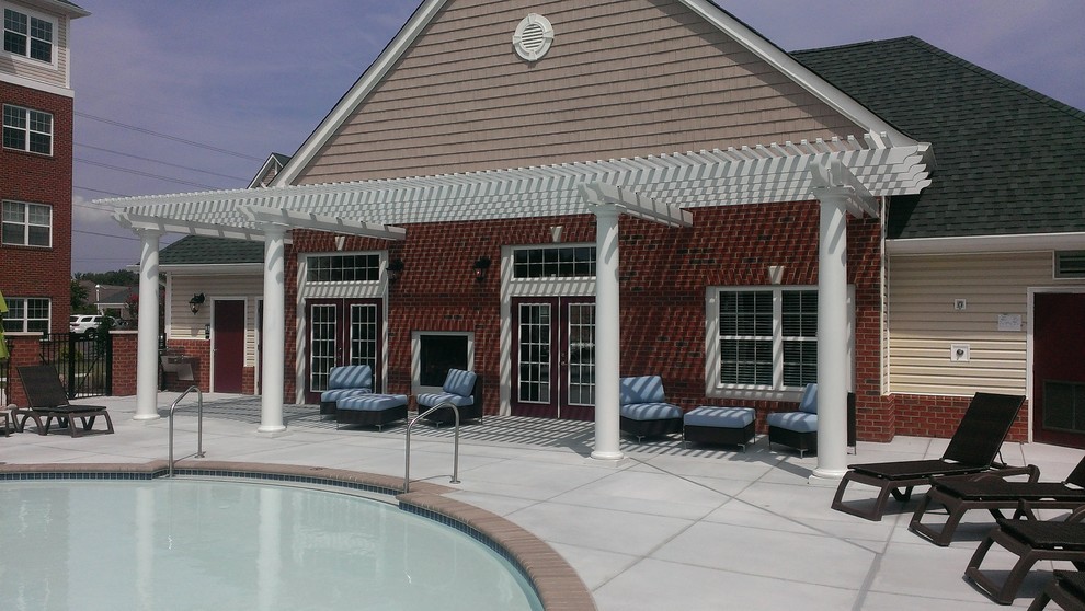 Foto di una grande piscina stile marino rotonda dietro casa con lastre di cemento e una dépendance a bordo piscina