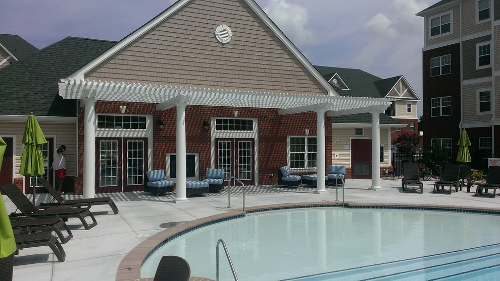 Esempio di una grande piscina stile marino rotonda dietro casa con una dépendance a bordo piscina e lastre di cemento