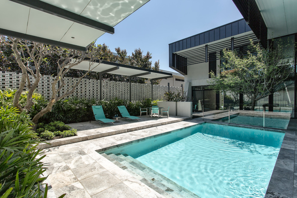 На фото: прямоугольный бассейн на заднем дворе в современном стиле с покрытием из бетонных плит